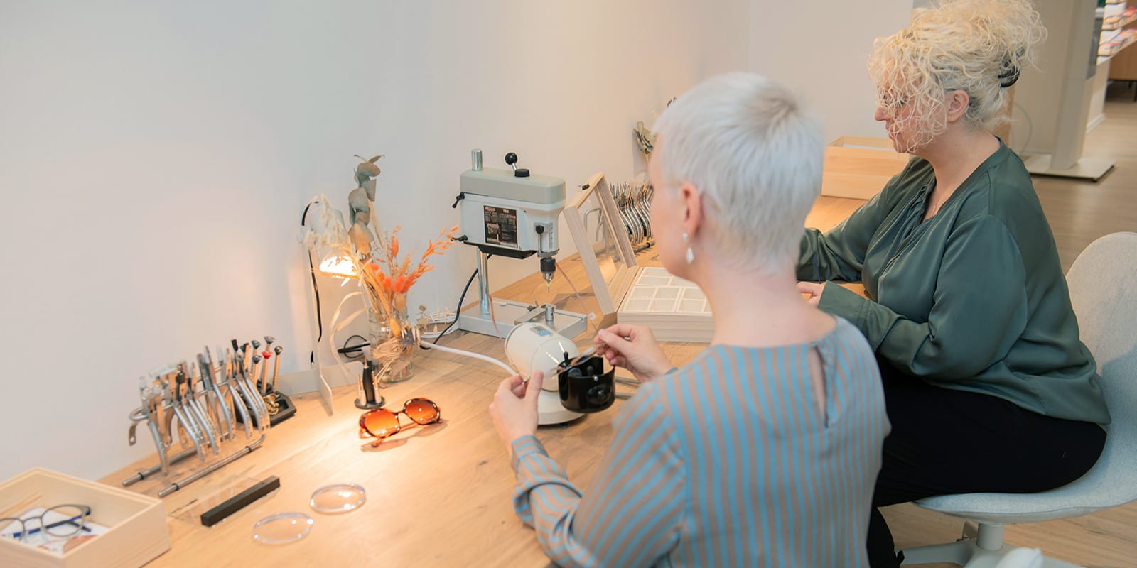 Zwei Frauen arbeiten an einem Holztisch mit verschiedenen Werkzeugen